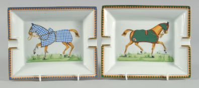 A PAIR OF HERMES PORCELAIN ASHTRAYS decorated with horses. 7.25ins long.