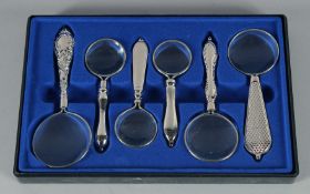A SET OF SIX SMALL MAGNIFYING GLASSES.