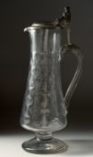 A GOOD TALL CLARET JUG AND COVER with pewter mounts. 15ins high.