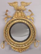 A REGENCY CARVED AND GILDED CIRCULAR CONVEX MIRROR. 1ft 7ins diameter with eagle surmount and pair