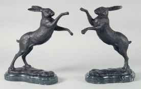 A PAIR OF BRONZE BOXING HARES on a shaped marble base.