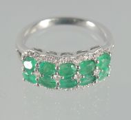 A SILVER AND EMERALD DOUBLE ROW RING.