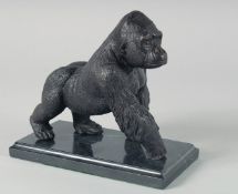 A BRONZE GORILLA on a marble base. 7.5ins long.