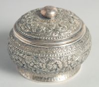 AN CAMBODIAN SILVER CIRCULAR LIDDED BOX, with embossed and engraved foliate decoration, stamped to