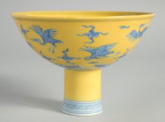 A CHINESE YELLOW GROUND BLUE AND WHITE STEM CUP, the exterior decorated with cranes and stylised
