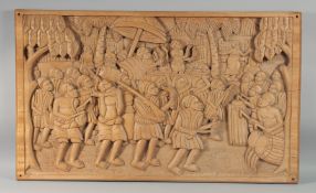 A LARGE BALINESE CARVED WOODEN PLAQUE, depicting a scene with a musical gathering, 62cm x 103cm.