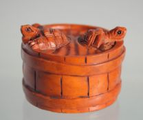 A JAPANESE BOXWOOD NETSUKE OF TORTOISES in a barrel.