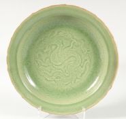 A CHINESE LONGQUAN PETAL FORM CELADON CHARGER, with carved dragon to the centre, 41cm diameter.