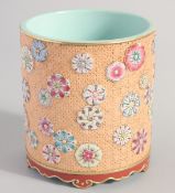 A CHINESE FAMILLE ROSE PORCELAIN BRUSH POT, decorated with raised floral motifs on a carved