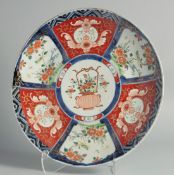 A JAPANESE IMARI PORCELAIN CHARGER, painted with panels of flora and central panel with a basket