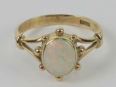 A contemporary 9ct gold and opal ring, the central oval cabachon having good multi colour fire,