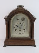 A late Victorian oak cased dome top table clock, silvered arch top dial with Arabic numerals,