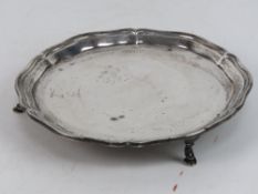 A HM silver card tray raised over three feet, 15.3cm dia, hallmarked Sheffield 1934, 169.4g.