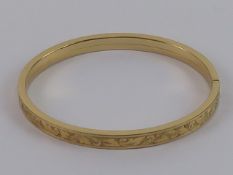 A vintage German rolled gold bangle having continuous leaf engraving.