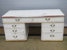 A white painted and part gilded low kneehole desk with drawers. 162 x 76cm.
