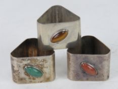 A set of three HM silver Modernist design triangular napkin rings each set with a different oval