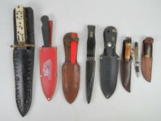 A quantity of assorted knives with scabbards.