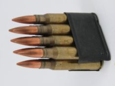 An M1 garand clip containing eight inert rounds. Bullets approx 8.5cm in length.