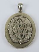 A large vintage white metal locket having BCH monogram to centre of leafy wreath, 5.4cm in length.