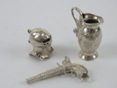 A large silver charm or pendant in the form of a jug having floral engraving upon, 3cm in length.