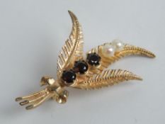 A 9ct gold brooch in the form of three leaves having three garnets and two pearls upon,