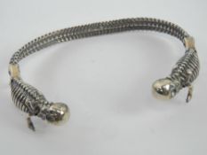 A silver Gothic bangle having skull terminals and bone / spine design throughout,