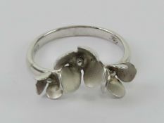 A silver floral ring having trio of flower buds on a wishbone band, stamped 925 with designers mark,