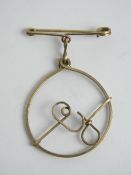 A vintage yellow metal brooch 'G' within circle suspended below safety pin style bar, 2.7cm wide.