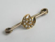 A vintage brooch, yellow metal, no apparent hallmark, having seed pearl crescent and star design,