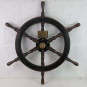 An early 20thC wooden ships wheel measuring 90cm handle-to-handle, bearing brass plaque upon.
