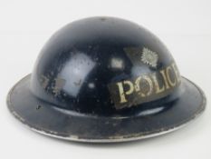 A WWII British police helmet with liner and chin strap, dated 1940.