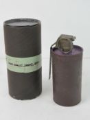 An inert US M18 smoke grenade in original casing with fuse and pin.