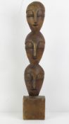 A carved wooden Totem in the form of three masks, standing 51.5cm high.