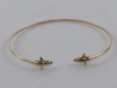 A 14ct gold bangle having dolphin terminals, stamped 585, 2.96g.