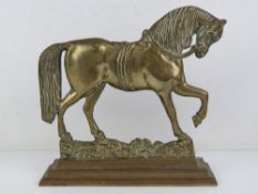 A heavy brass doorstop in the form of a horse, 24cm wide.