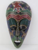 A carved and ebonised wall mask having Aboriginal type dot paint Pointillism decoration upon,