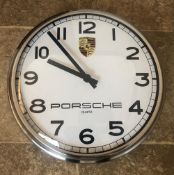 A Porsche themed dealer-type wall clock. White dial with black baton hands and Arabic numerals.