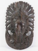 A carved and pierced oriental hardwood 'mask' of a female in ceremonial headdress, possibly Tibetan,