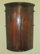 A Georgian barrel fronted hanging corner cabinet.