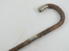 An early 20th century bamboo walking cane having silver collar and end cap,