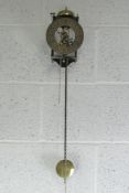 A contemporary wall clock having brass skeleton movement with weight and pendulum.