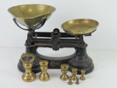 A set of black painted balance scales with brass pans and set of brass weights 1/4oz to 1lb.