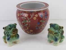 A contemporary Chinese influence red ground fish bowl type planter together with two Fo dog