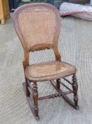 A cane seated rocking chair.