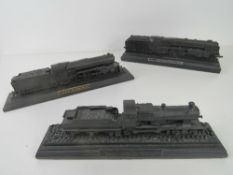 Three decorative carved coal model trains.
