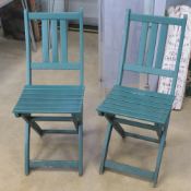 A pair of green painted wooden garden bistro chairs.