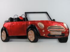 A large contemporary metal wall hanging in the form of a red mini.