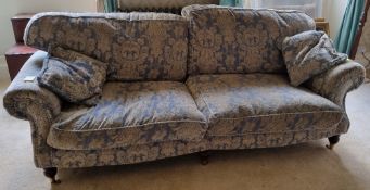 A Victorian style scroll arm settee raised over turned legs terminating in brass castors.