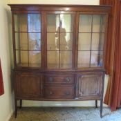 An Edwardian glazed two door display cabinet raised over the solid base having two central drawers