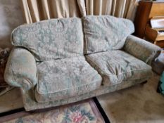 A Victorian style two seater scroll arm settee raised over short legs terminating in brass castors.
